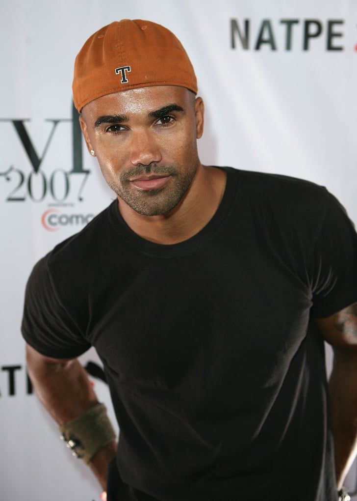 a man in a black shirt and orange hat posing for the camera with his hands on his hips