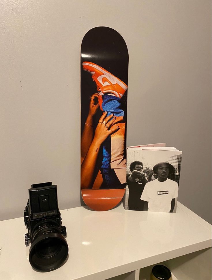 a skateboard sitting on top of a table next to a camera and some photos