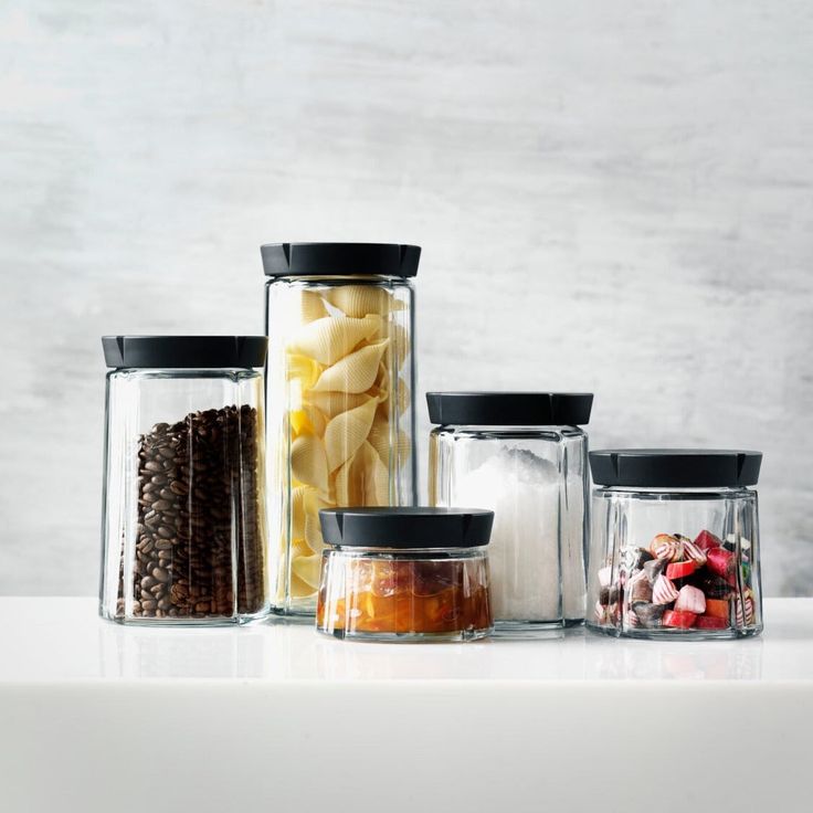 four glass containers with food in them sitting on a white countertop next to each other