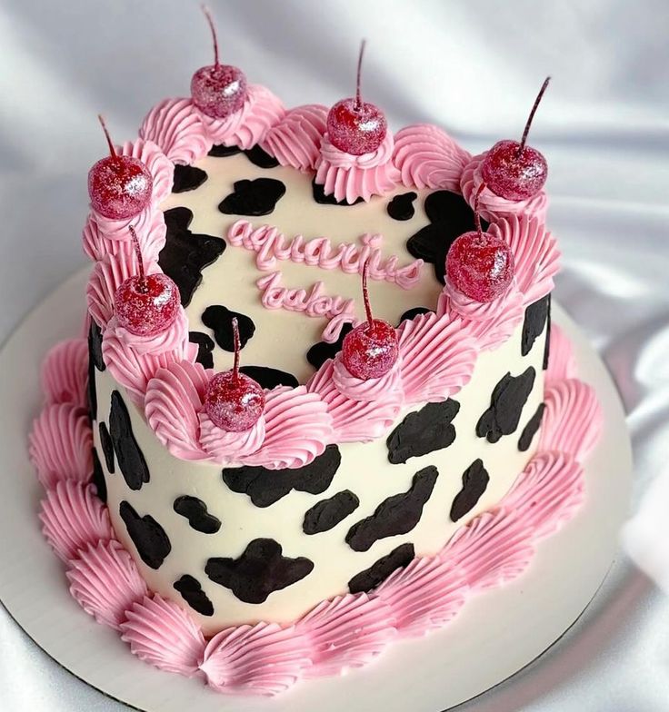 a pink and black cake on a white plate with the words happy birthday written on it