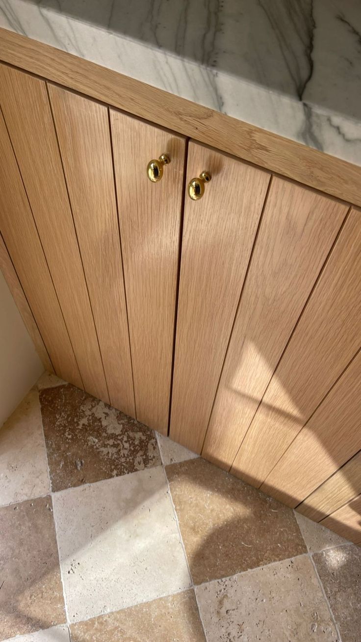 a wooden cabinet sitting next to a counter top on a tiled floor in a kitchen