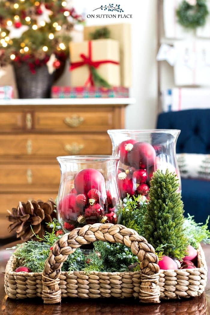 two glass vases filled with ornaments on top of a wooden table in front of a christmas tree