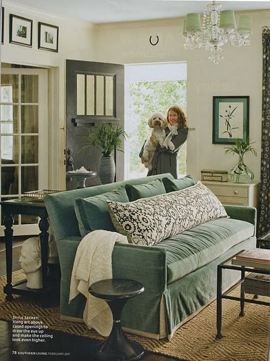 a woman holding a dog in her arms while standing next to a couch and coffee table