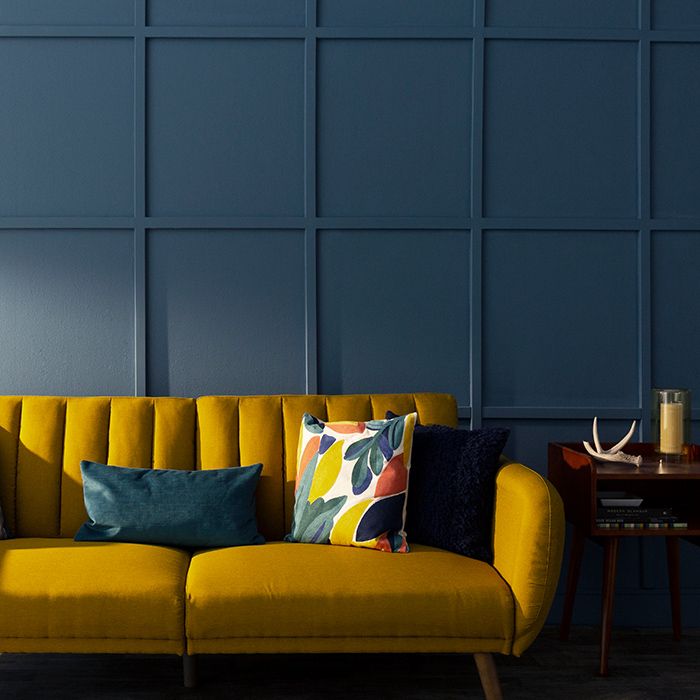 a yellow couch sitting in front of a wall with blue panels on the back and sides