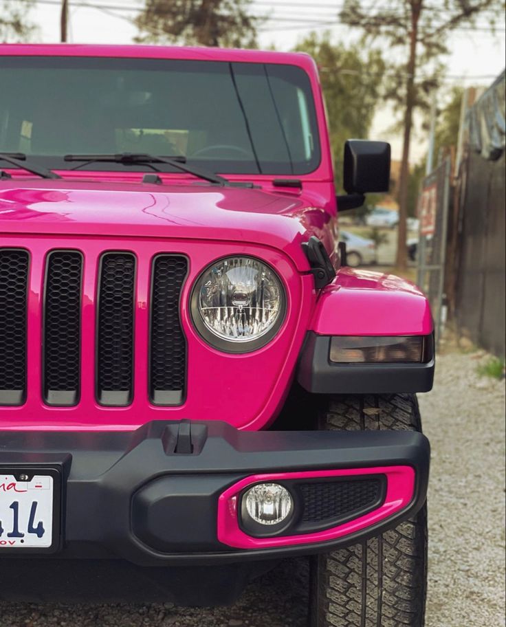 a bright pink jeep is parked on the side of the road with it's license plate