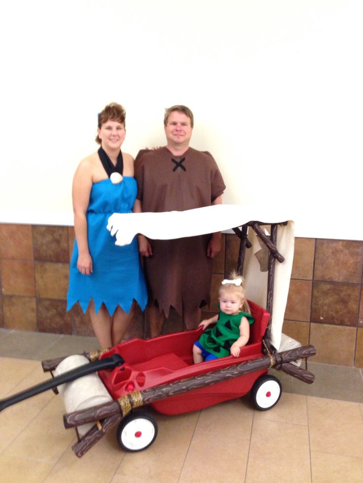 a man and woman standing next to a baby in a wagon