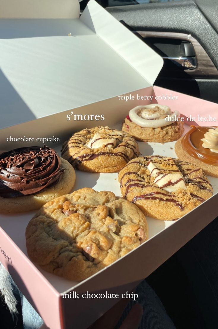 a pink box filled with lots of different types of cookies and pastries on top of each other