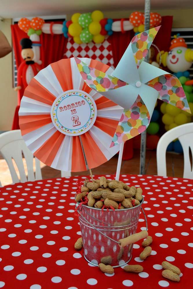 a red table topped with a tin can filled with peanuts and a pinwheel decoration