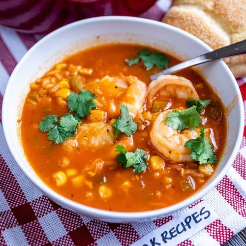 a bowl of soup with shrimp, corn and cilantro