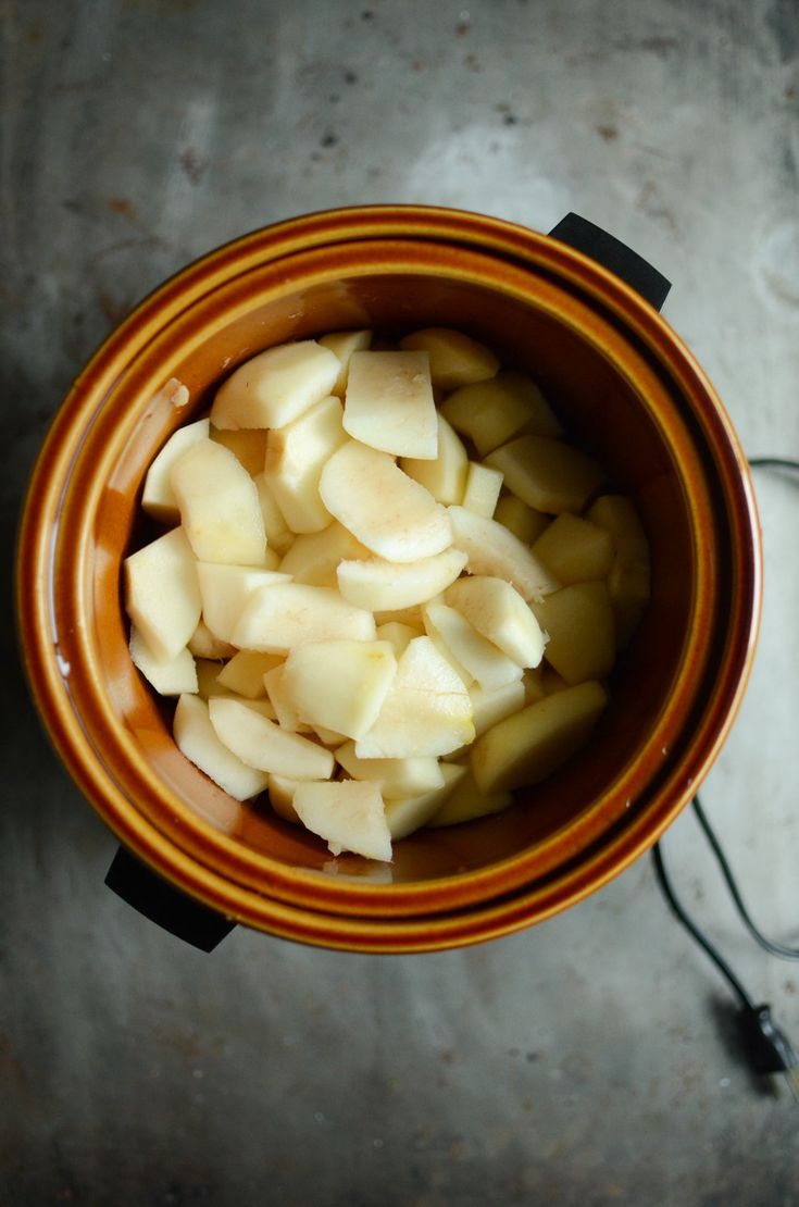 a brown bowl filled with sliced apples on top of a table