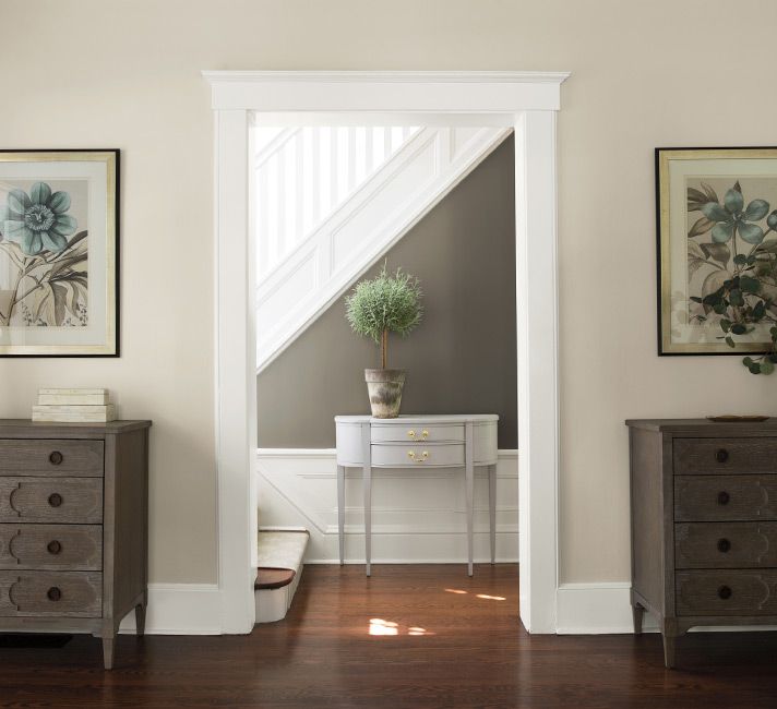 an entry way with two dressers and a potted plant on the table next to it