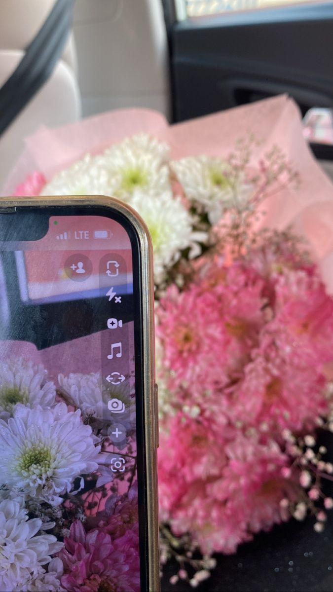 a bouquet of flowers sitting next to a cell phone in the back seat of a car