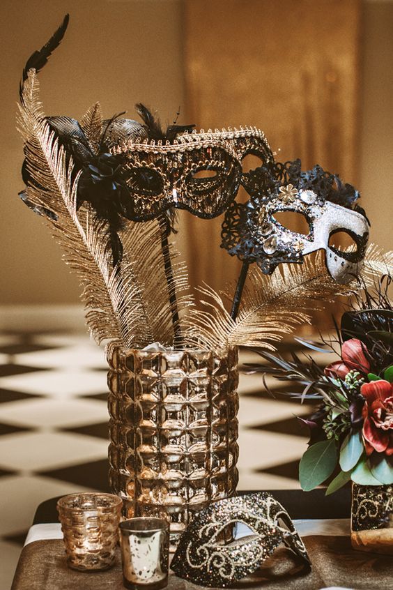 a table topped with a vase filled with flowers and masks