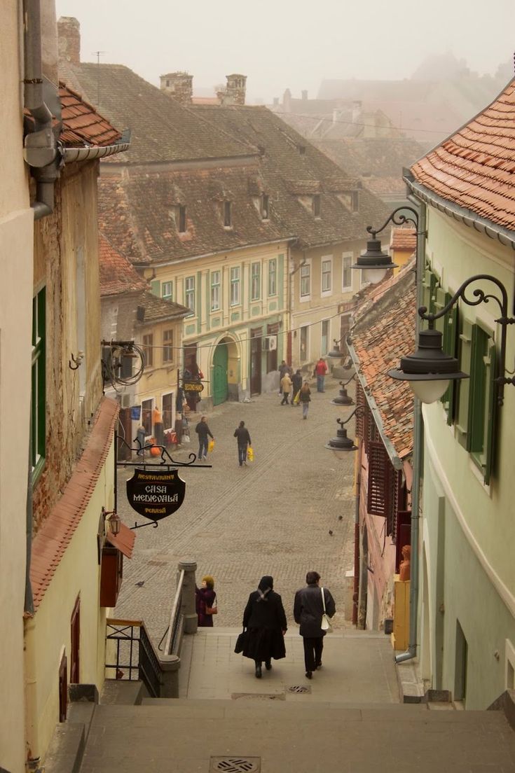 two people are walking down the stairs in an old town with cobblestone streets