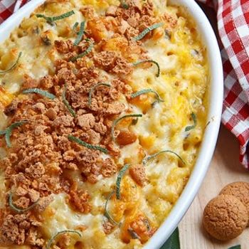 a casserole dish with meat and cheese in it on a wooden table next to breadcrumbs