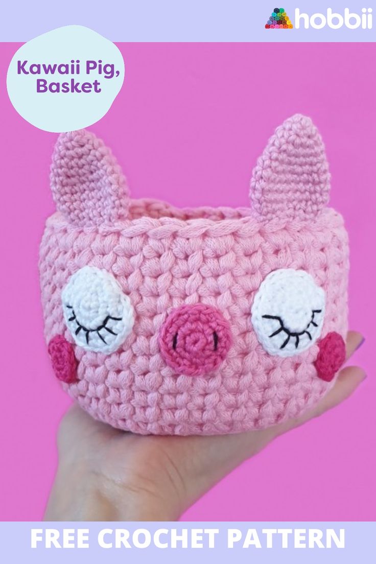 a pink crocheted pig purse with eyes and ears on it's face