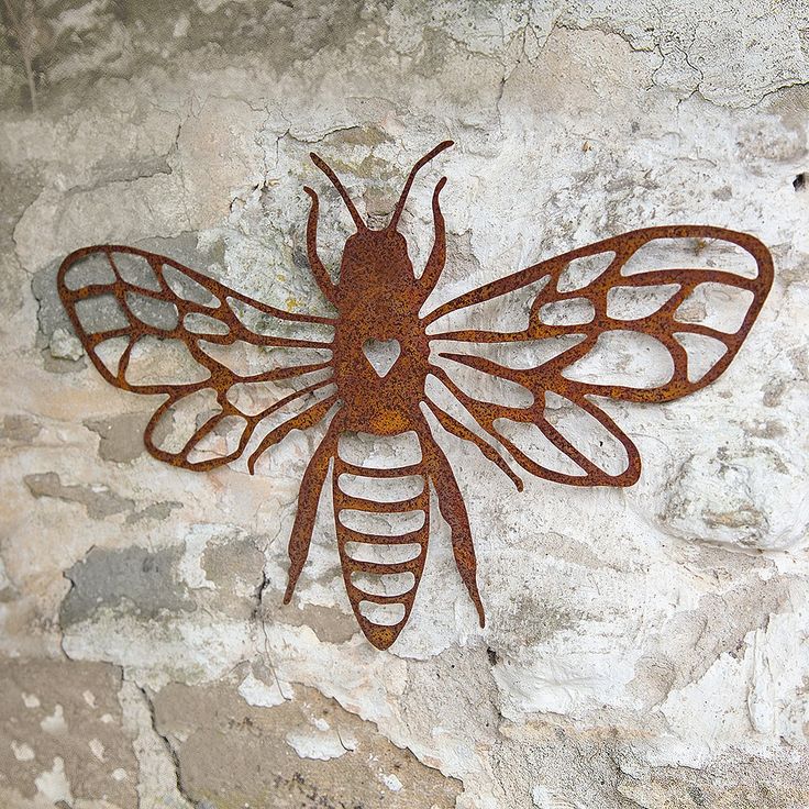 a rusted metal insect sitting on top of a stone wall