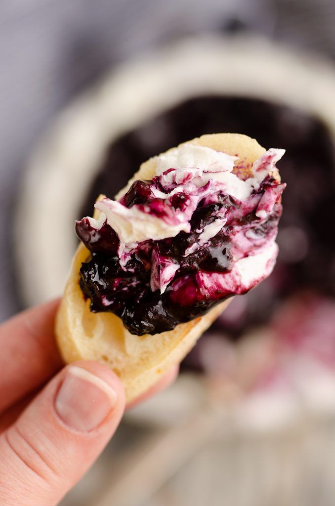 blueberry cheese appetizer is being held up in front of the camera and text reads, blueberry balsamic goat cheese appetizer