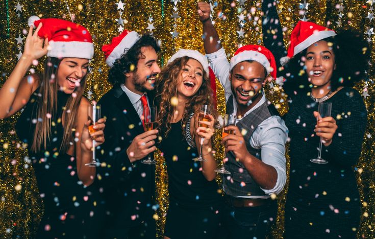 a group of people wearing santa hats and drinking champagne