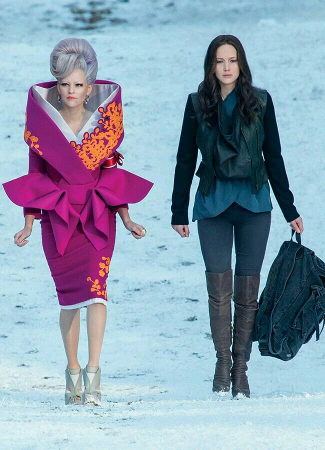 two women walking in the snow with one carrying a bag and another holding a purse