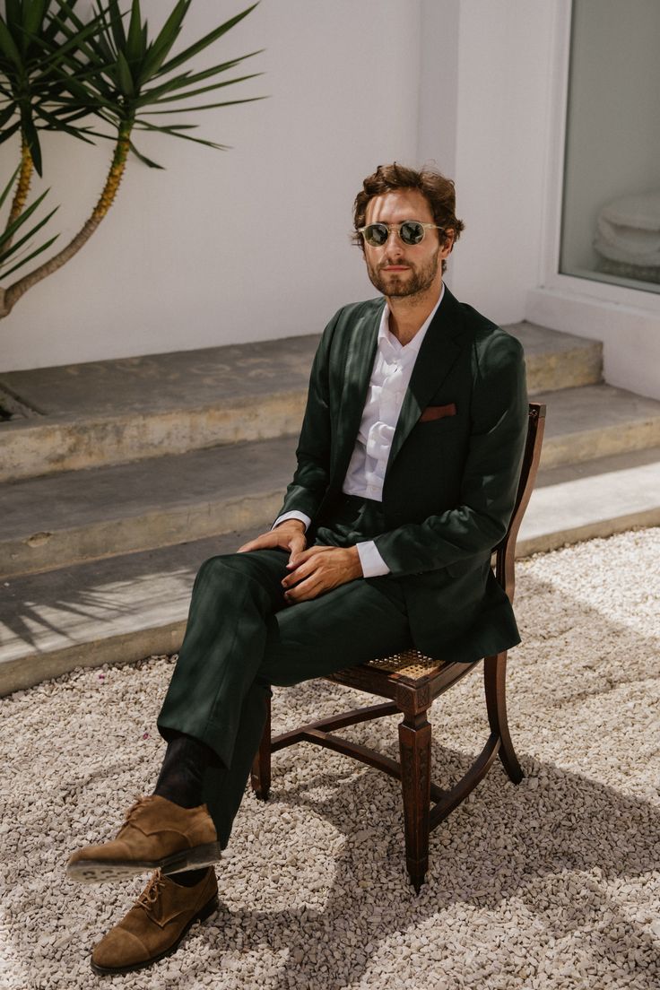 a man sitting on top of a wooden chair next to a potted palm tree