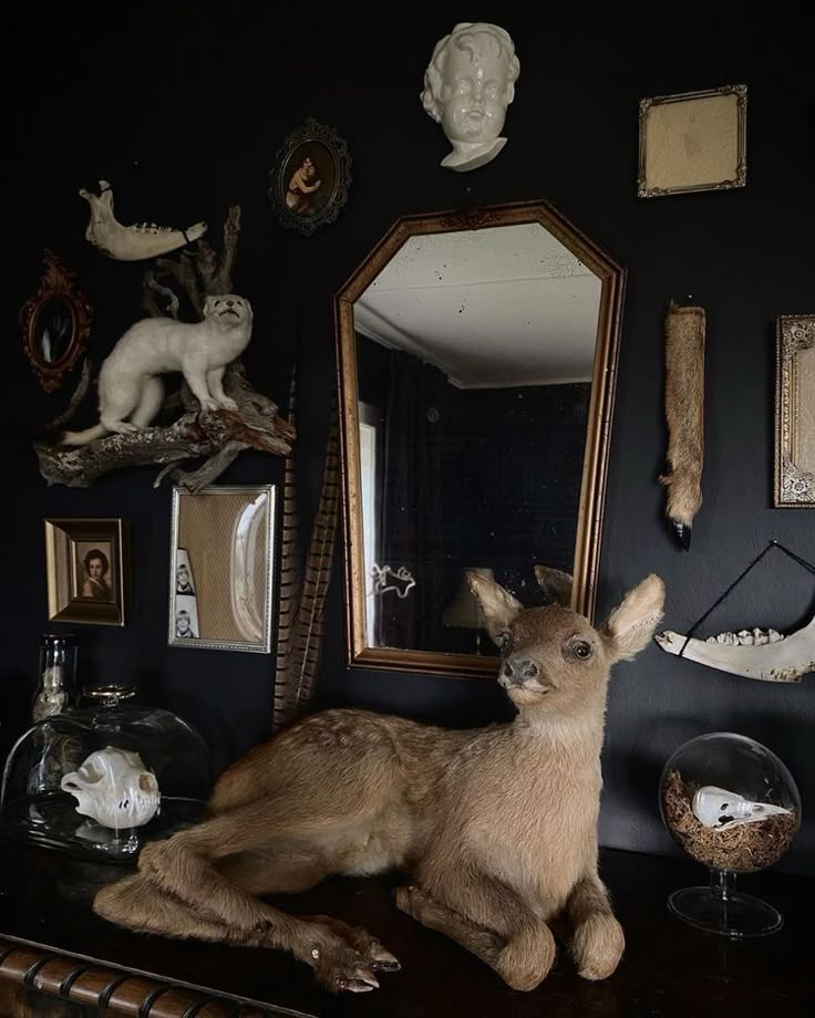 a deer statue sitting on top of a table next to a mirror and other animal figurines