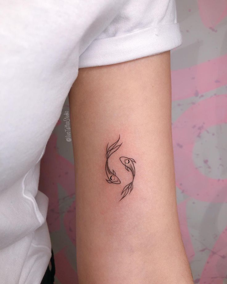 a woman's arm with a small black fish tattoo on the left side of her arm