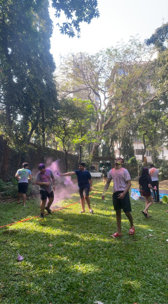 some people are playing with colored powder in the grass on a sunny day at a park