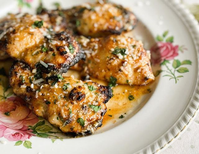 a white plate topped with chicken covered in sauce and parmesan sprinkles