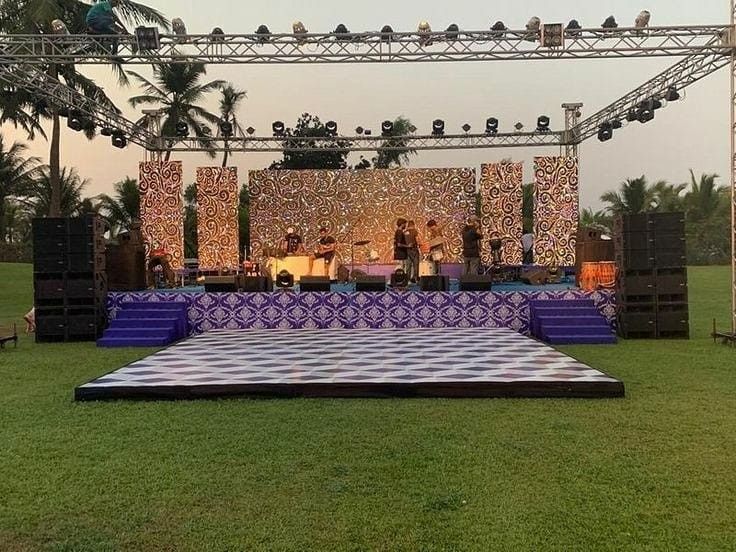 an outdoor stage set up in the middle of a field with people standing on it