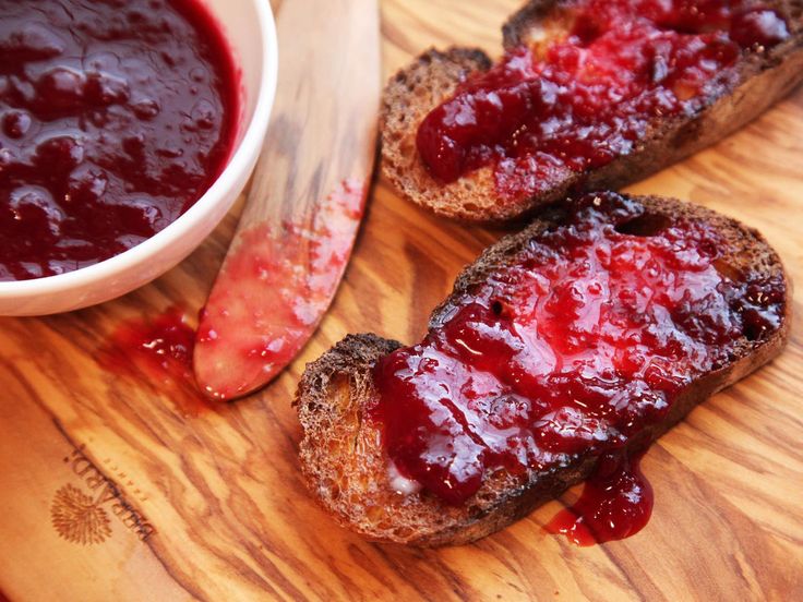 two pieces of bread with jam on them next to a bowl of ketchup