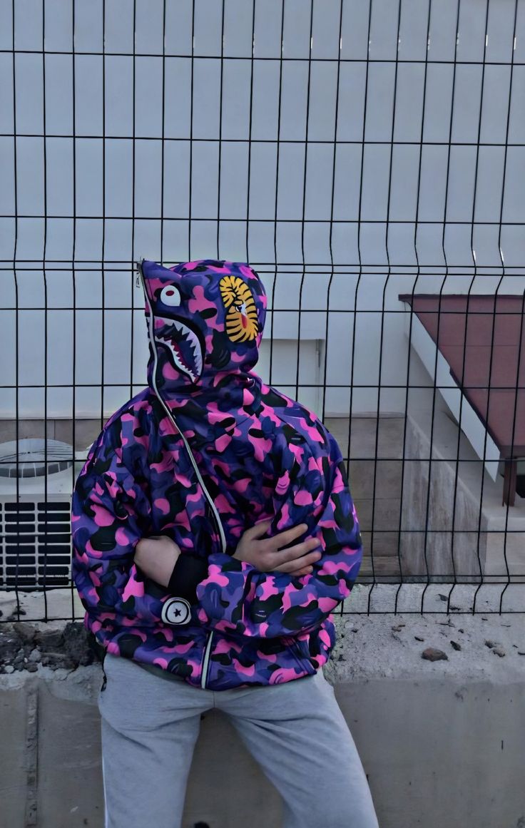 a young boy wearing a purple and black jacket with a shark head on it's hood