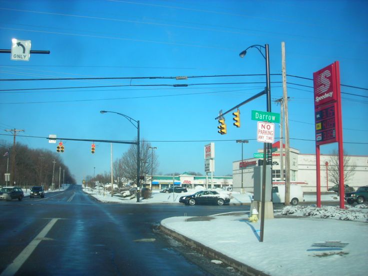 a street with cars parked on the side of it and traffic lights in the background