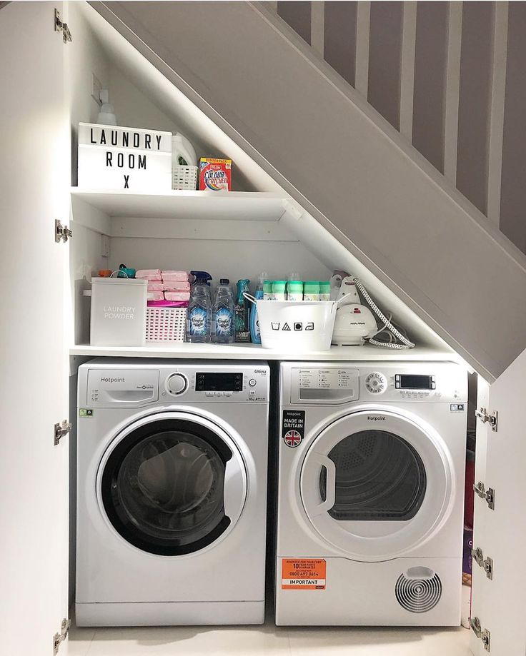 a washer and dryer are under the stairs in this small laundry room area