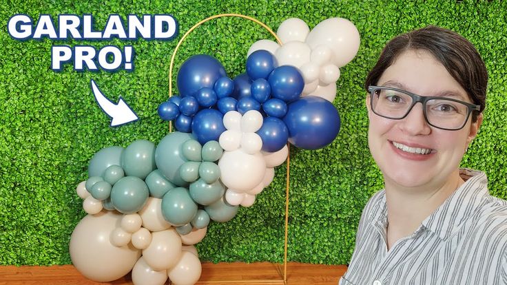 a woman standing in front of a green wall with balloons on it and the words garland pro above her