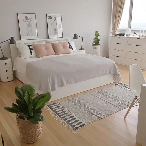 a bedroom with white walls and wooden flooring has a large bed in the center