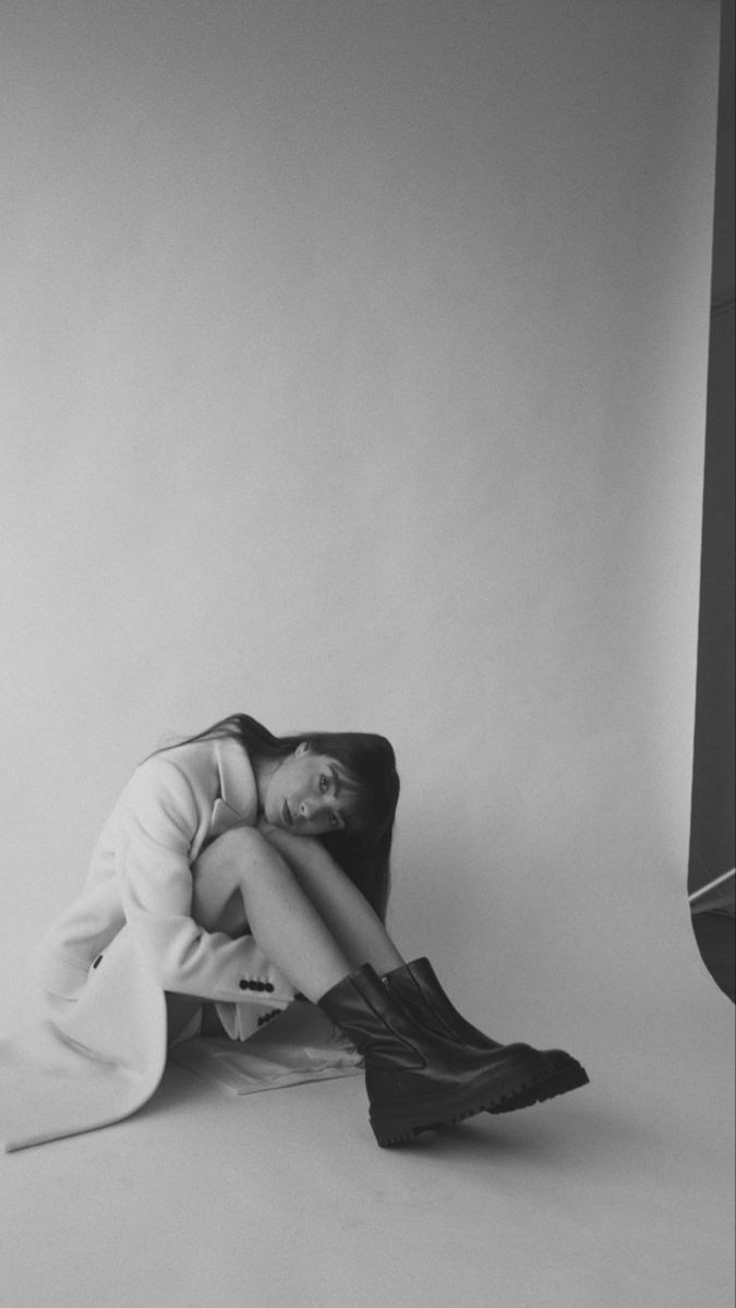 a black and white photo of a woman sitting on the floor with her legs crossed