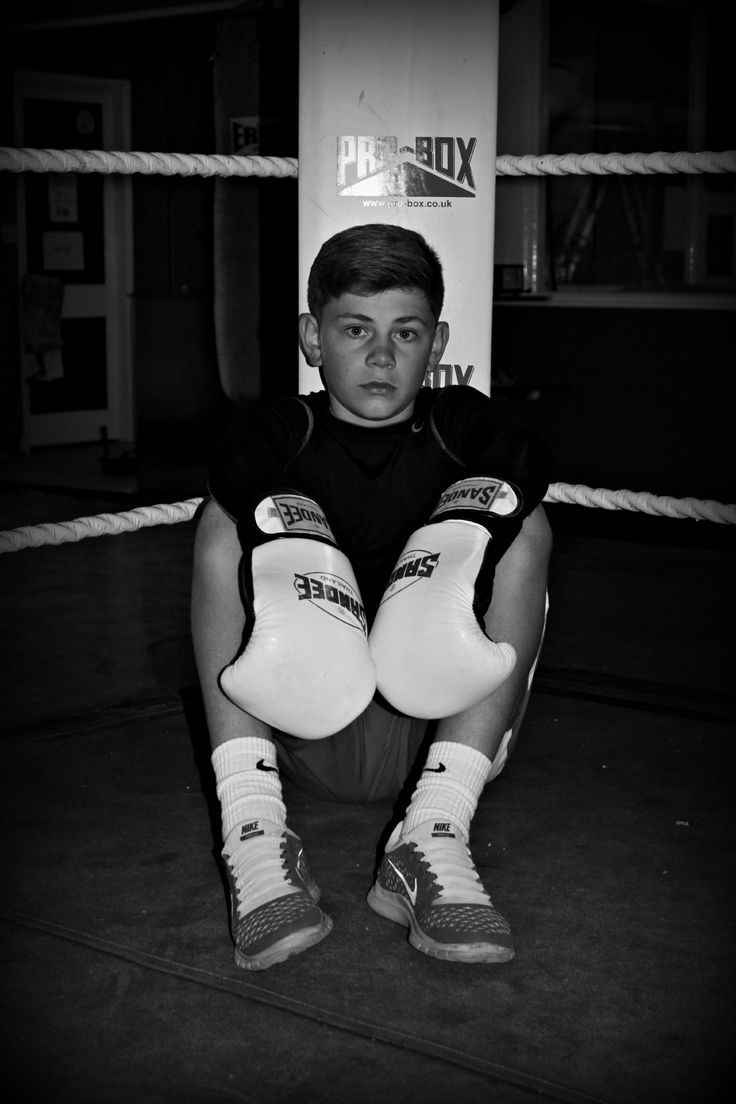 a young man sitting on the ground wearing boxing gloves