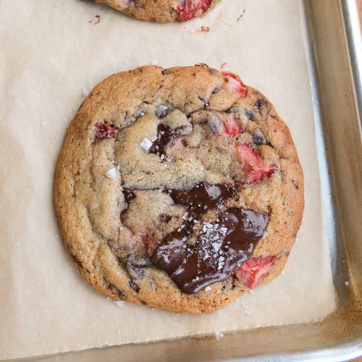 two chocolate chip cookies sitting on top of a cookie sheet covered in icing and jelly