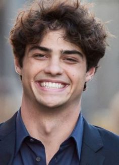 a smiling young man in a blue shirt and blazer