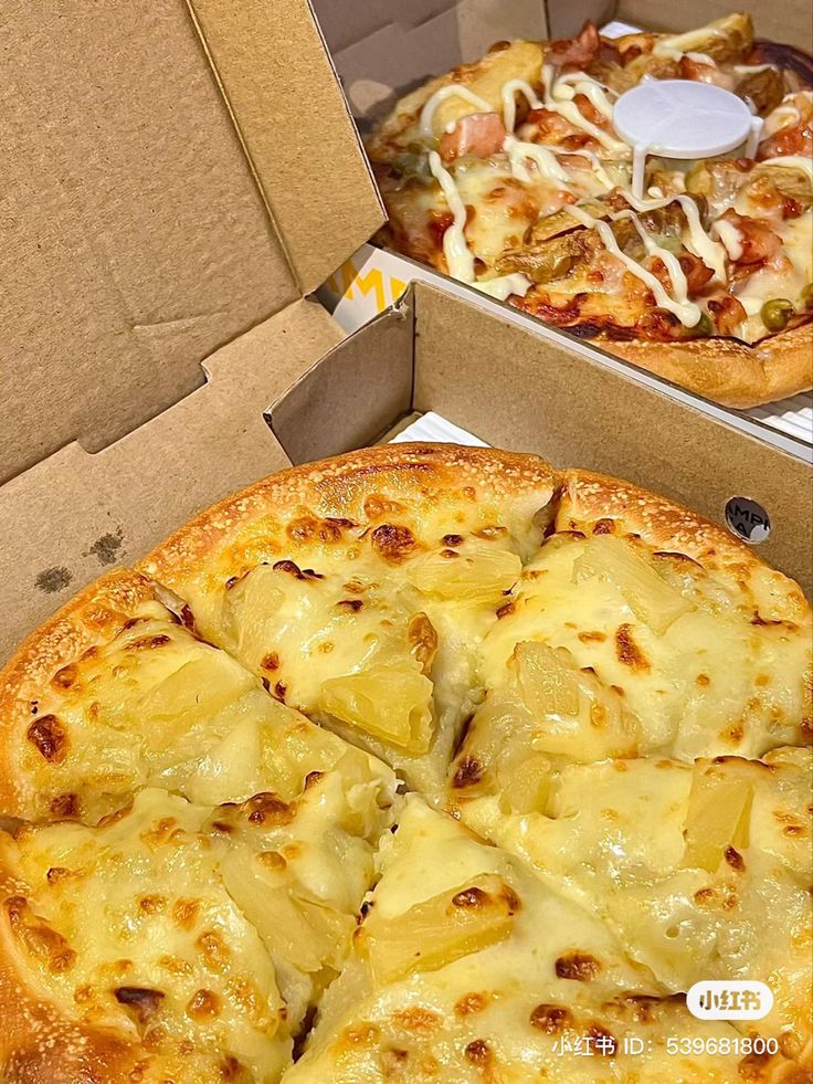 two pizzas with pineapple on them are in the box and ready to be eaten