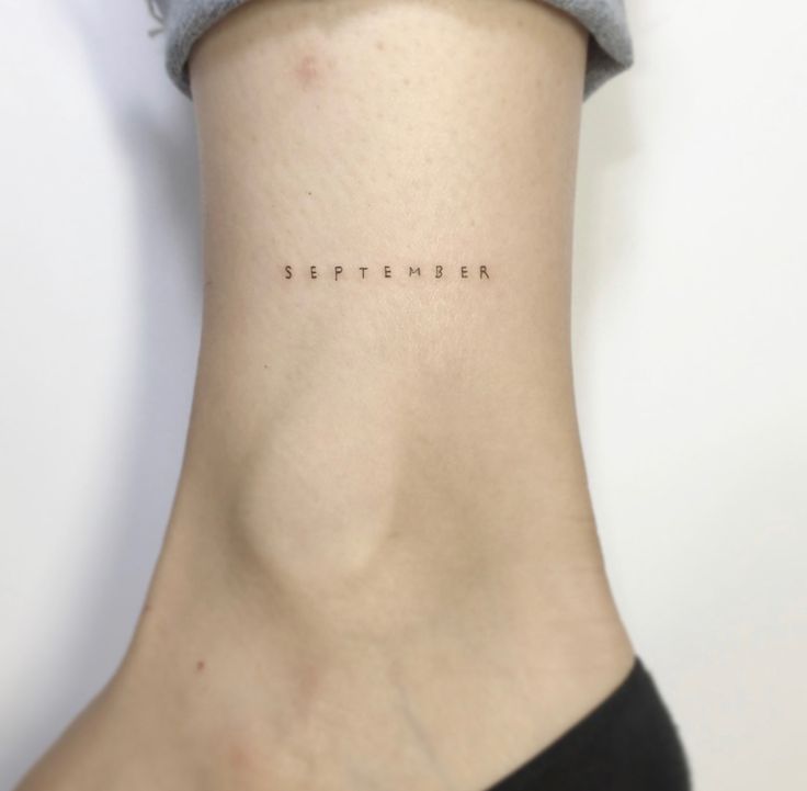 a woman's neck with the word september written on her left side ribcage