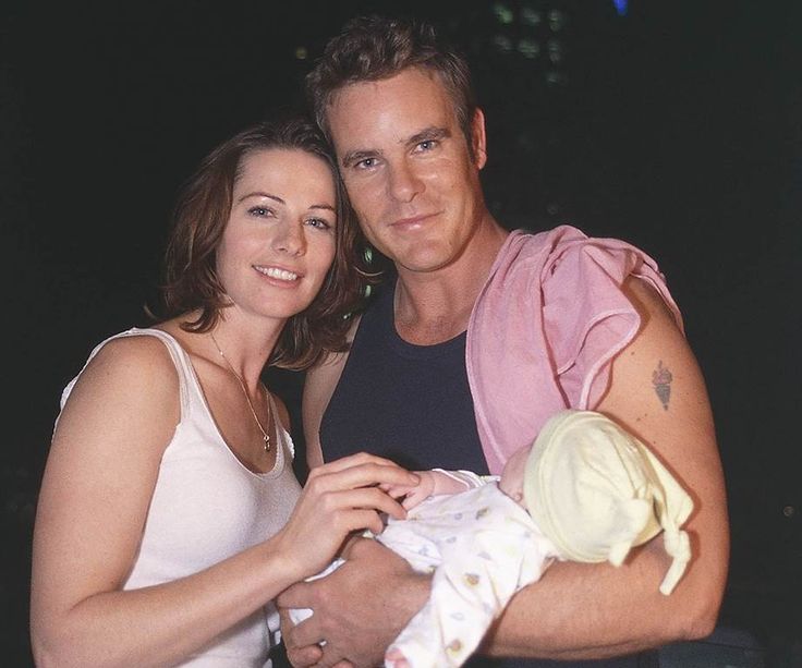 a man holding a baby next to a woman