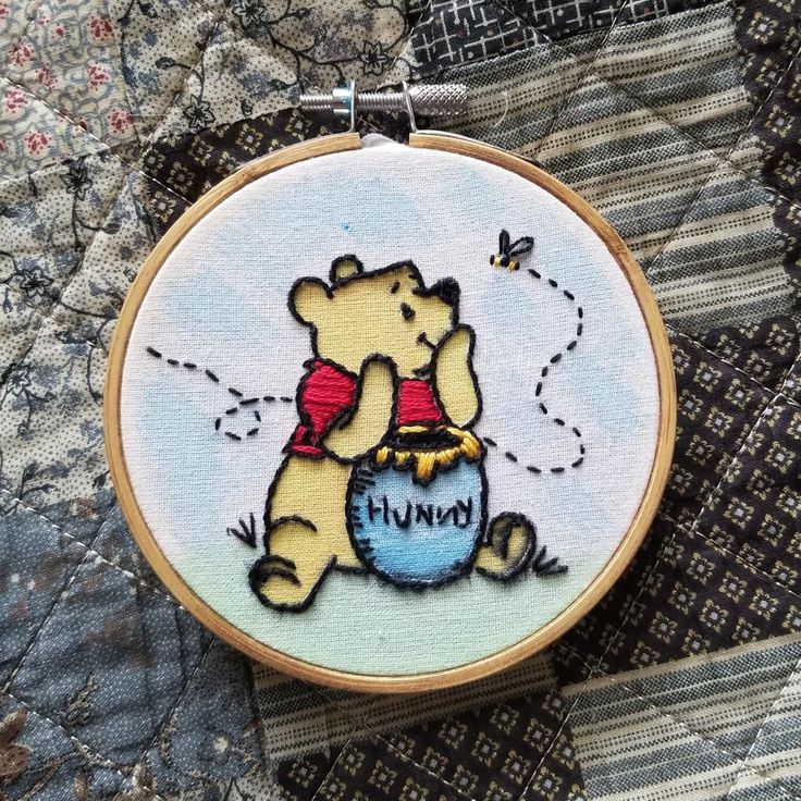 a winnie the pooh cross stitched into a piece of fabric on top of a quilt