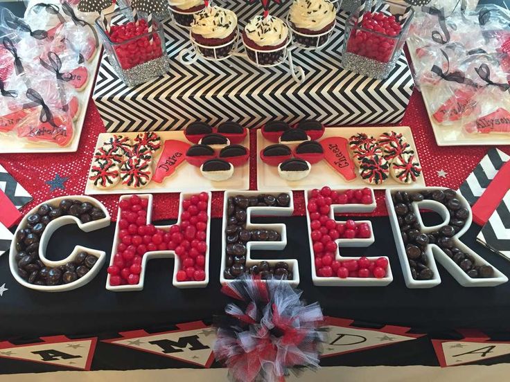 a dessert table with cupcakes, candy and other treats on it that spell out the word cheer