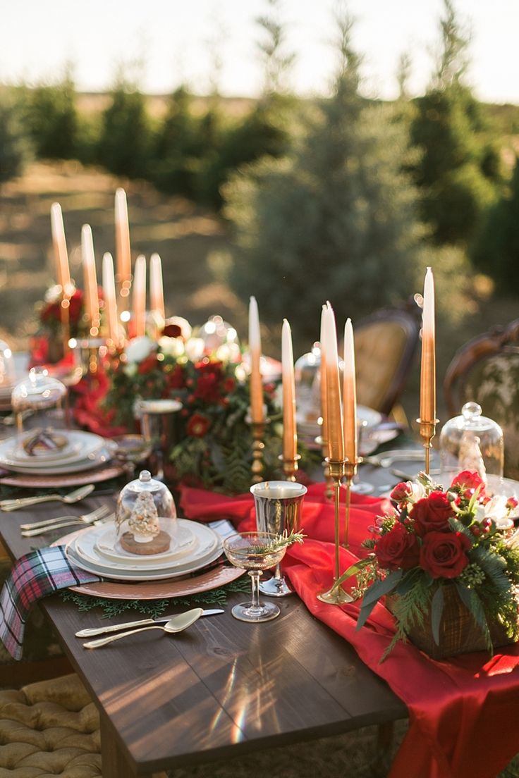 the table is set with candles, plates and napkins for an elegant outdoor dinner