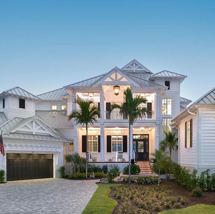 a large white house with palm trees in the front yard and landscaping on both sides