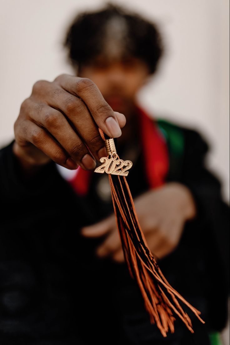 a person holding a tassel with the word love on it