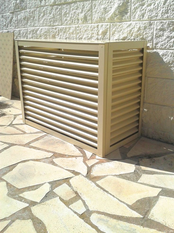 a large wooden slatted window on the side of a building next to a stone walkway