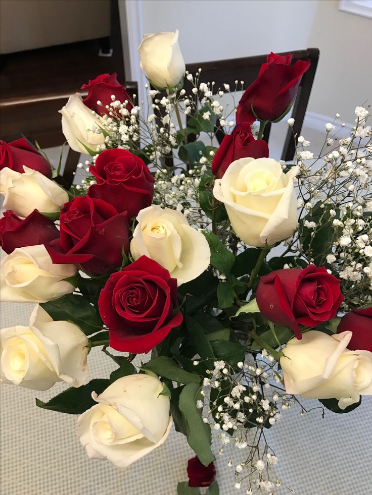 a vase filled with white and red roses